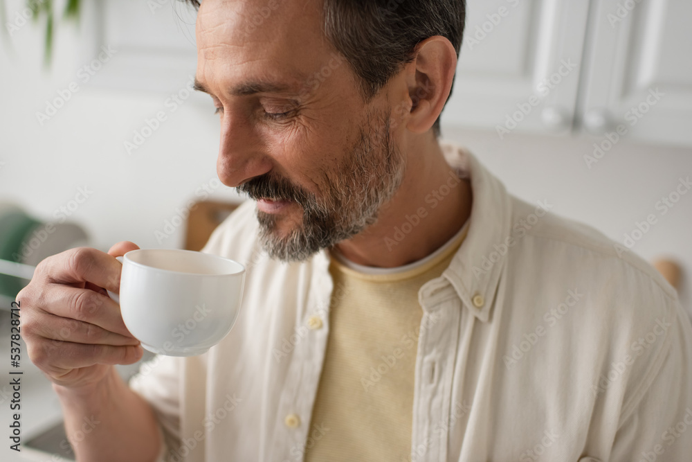 bearded man in white shirt enjoying flavor of morning coffee at home. bearded man in white shirt enjoying flavor of morning coffee at home.