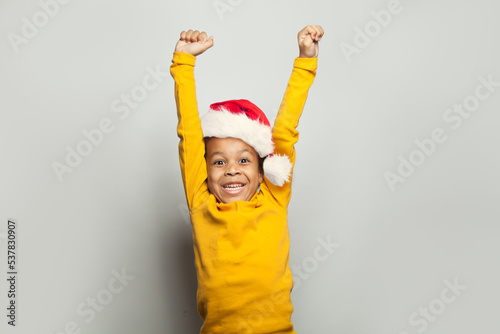 Little black child win-win! Kid boy in Santa hat having fun on white background