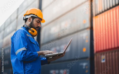 Container operator holding a laptop while working in container yards.