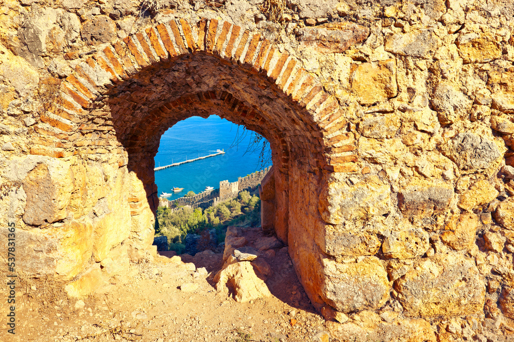 Ancient stone wall of Alanya Castle, view of the bay through the arch. Alanya, Antalya Province, Turkey