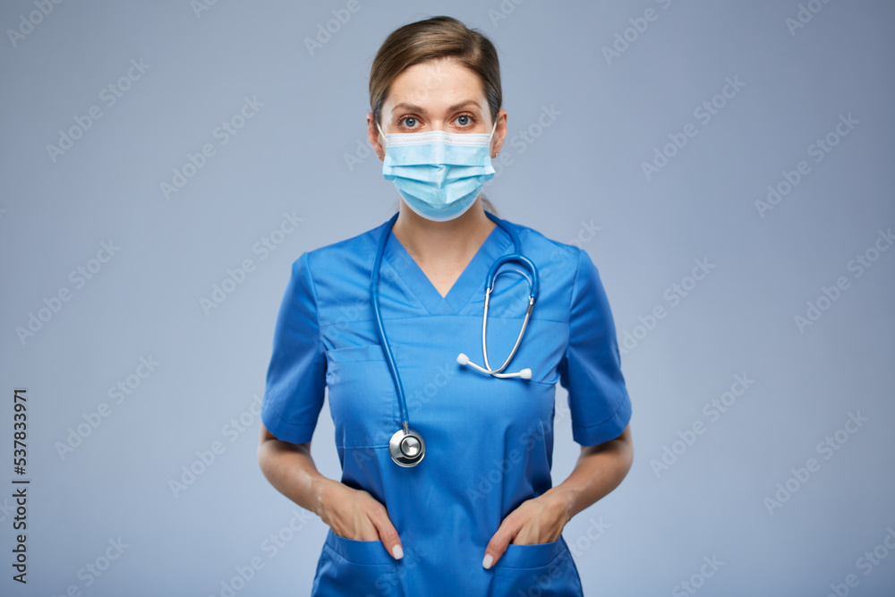 Serious nurse woman or doctor in blue medical mask and suit. Isolated female portrait. Serious nurse woman or doctor in blue medical mask and suit. Isolated female portrait.