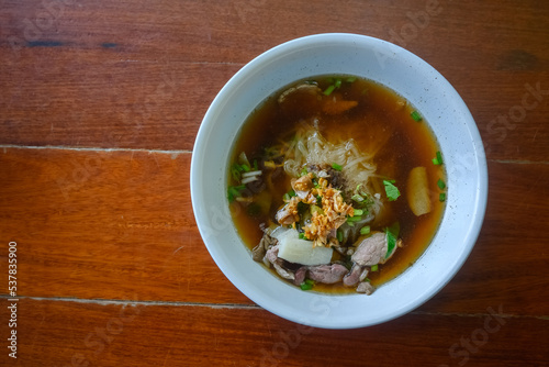 Asian delicatessen, beef noodles with soup on wood table.