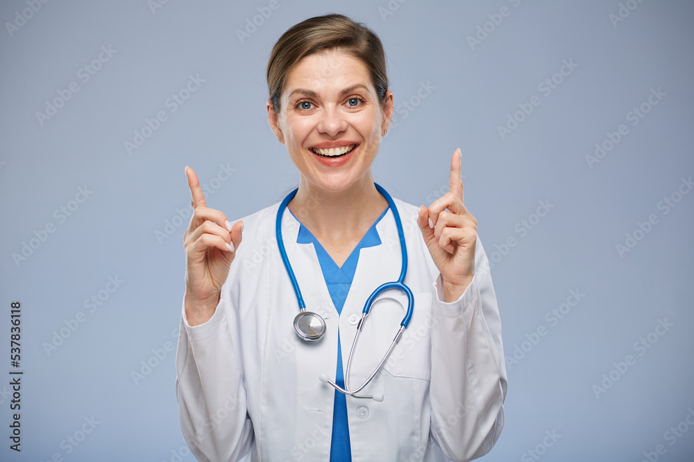 Smiling doctor woman in white lab coat pointing with two fingers up isolated portrait. Smiling doctor woman in white lab coat pointing with two fingers up isolated portrait.