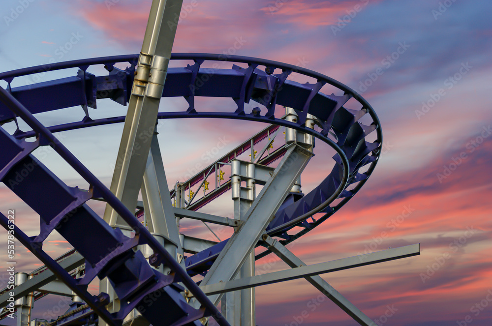 Attraction roller-coaster (switchback) against the background of a romantic evening sky