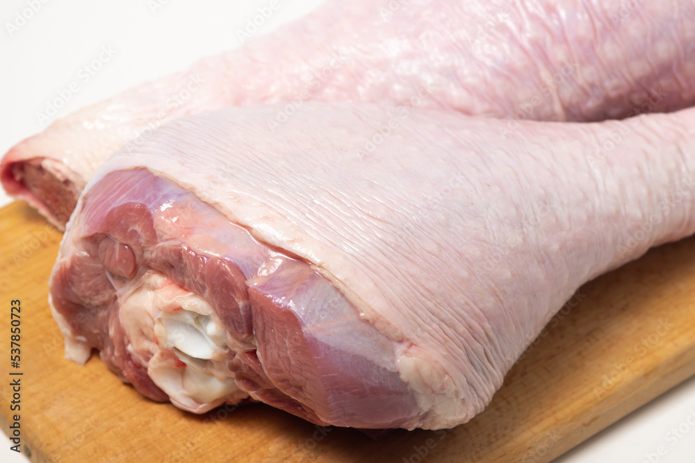Raw turkey leg on a wooden board on a white background. Fresh turkey meat Raw turkey leg on a wooden board on a white background. Fresh turkey meat