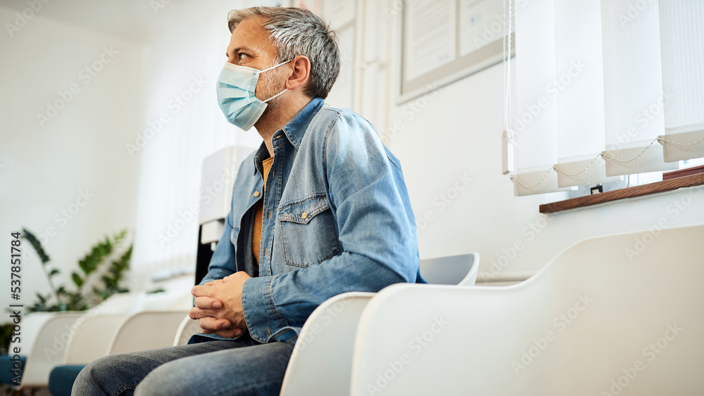 Man with protective face mask sitting in waiting room at medical clinic. Man with protective face mask sitting in waiting room at medical clinic.