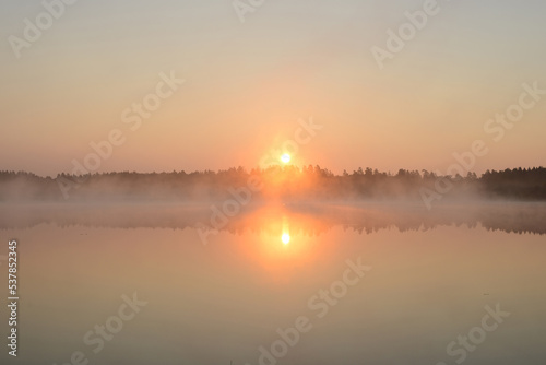Fototapeta Naklejka Na Ścianę i Meble -  Sunrise on a forest lake. Beautiful foggy morning nature landscape. Calm scene. Dawn, mist, calm water