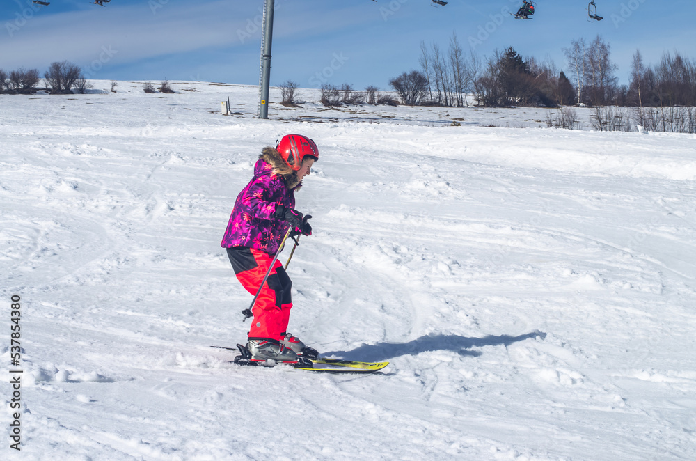 little girl skiing downhill in snowy resort