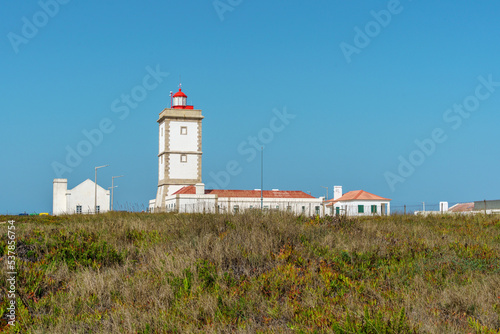 white lighthouse building a sentinal beacon on a rocky shoreline photo
