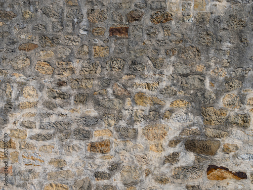 Old stone wall texture with different natural stones. Abstract background from a building exterior. Weathered rough masonry pattern of the material. Vintage architecture in a rural area.
