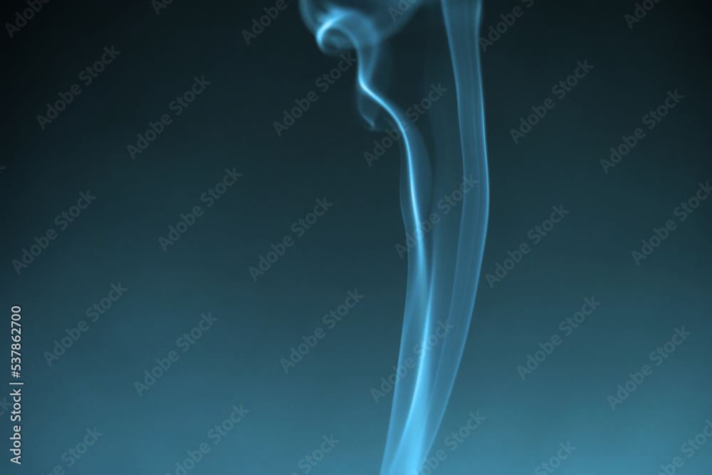 Illuminated blue green smoke of incense stick against black background. Photo taken October 13th, 2022, Zurich, Switzerland.