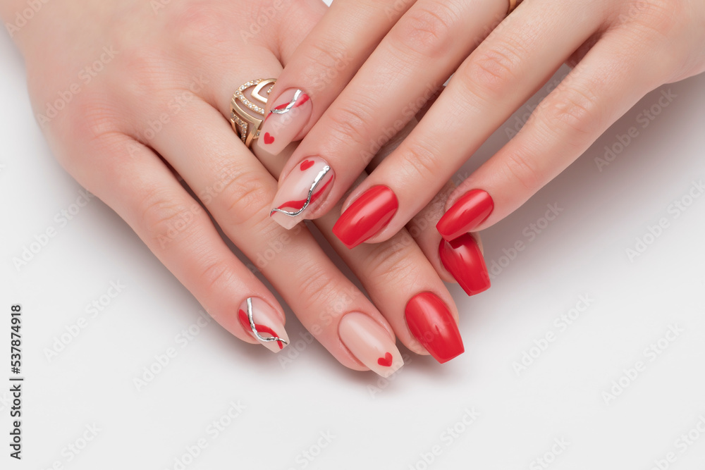 Red, beige manicure with hearts, gold casting, red stripes, waves on long square nails on a white background close-up Red, beige manicure with hearts, gold casting, red stripes, waves on long square nails on a white background close-up