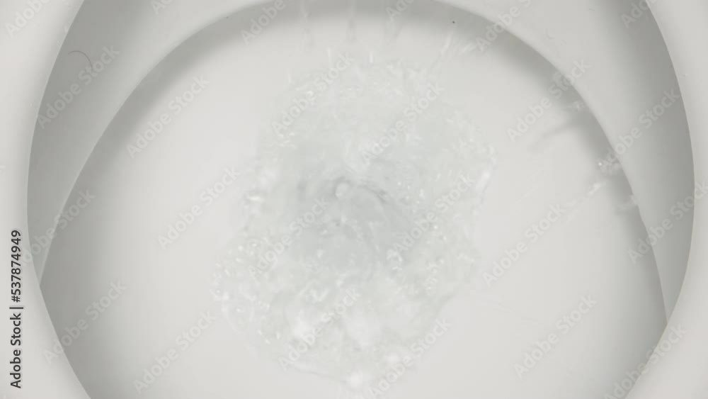The camera looks into the toilet while the water is being flushed there. Close-up The camera looks into the toilet while the water is being flushed there. Close-up