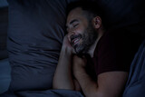 Happy man falls asleep in a good mood in a gray bed at night