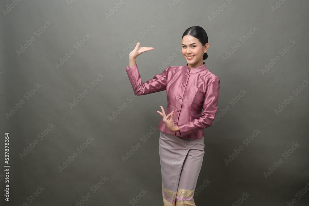 A young asian woman wearing Thai traditional cloth on gray background