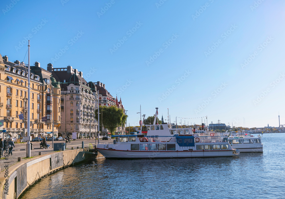 Commuting boats at a pier in the bay Nybroviken a sunny a color full autumn day in Stockholm