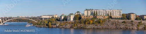 Panorama view at a bay of the lake Mälaren, water front apartment houses on a cliff and a long high bridge a sunny a color full autumn day in Stockholm