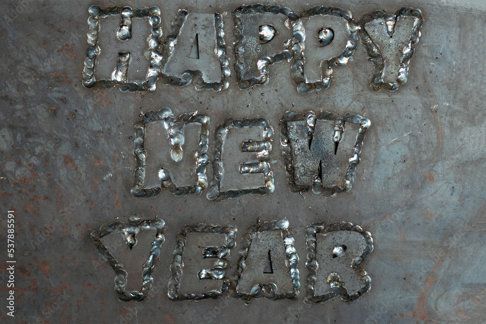 A stern happy new year phrase made from steel letters welded to a steel sheet. Unusual New Year's card A stern happy new year phrase made from steel letters welded to a steel sheet. Unusual New Year's card
