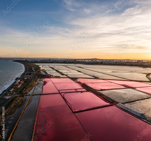 Drone shot of a salmon red waters near saltworks at sunset