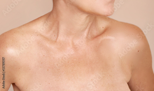senior women's neck shoulder lips and collarbone on nude background 
