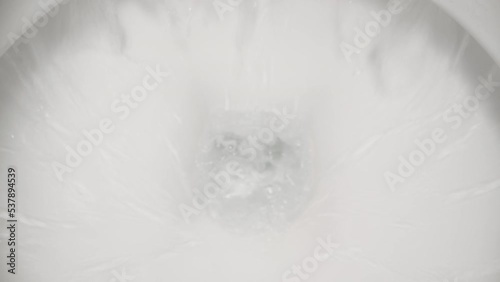 The camera plunges into the toilet while the water is flushed there. Dolly slider extreme close-up.