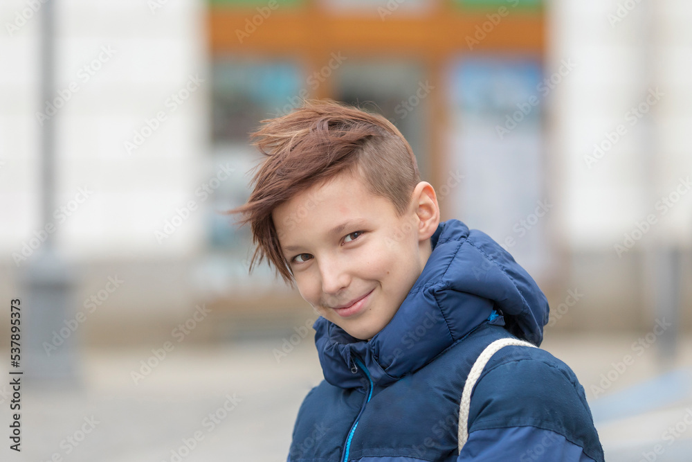 Portrait of a smiling boy on the street in a blue jacket