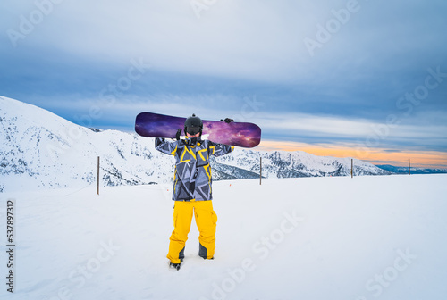 Portrait of a man snowboarder holding a snowboard on the top of the snowy Pyrenees Mountains. El Tarter, Grandvalira, Andorra photo