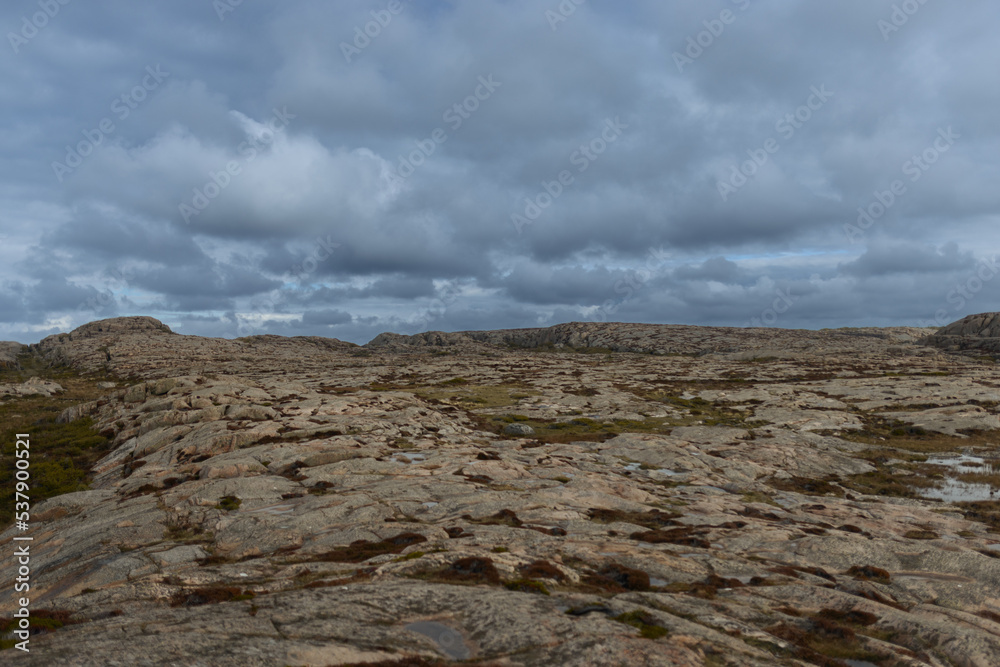 An empty rocky landscape with dramatic clouds in the sky.