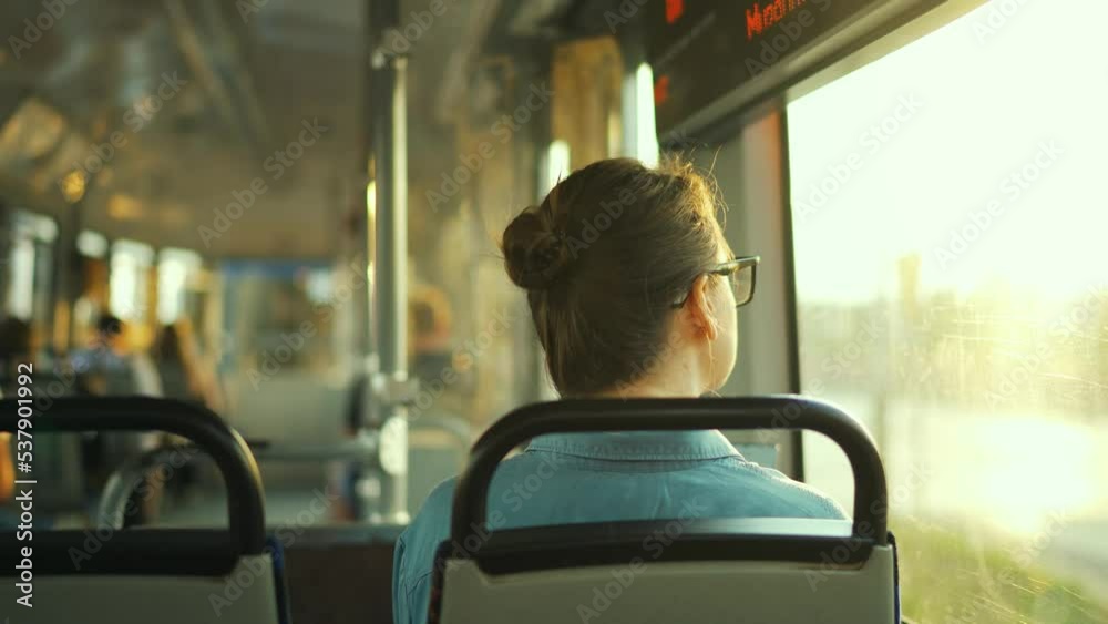 Woman with glasses in a tram looking out the window. City, urban, transportation
