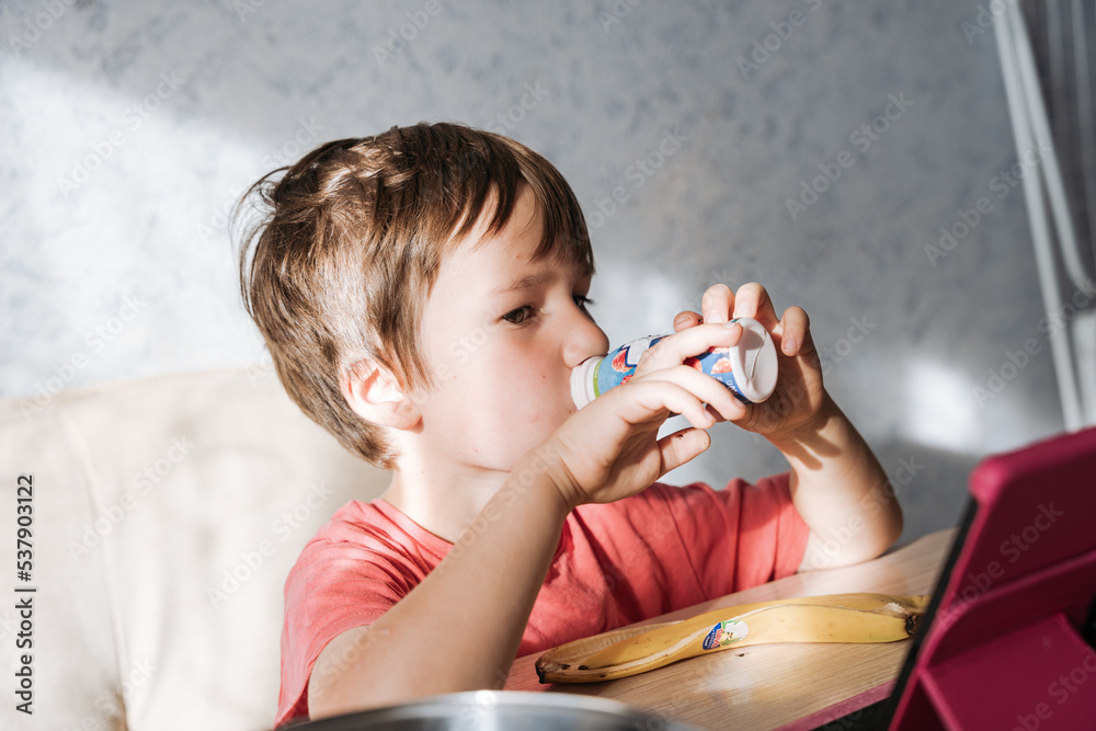 custom made wallpaper toronto digitalSmall boy drinking yoghurt and watching tablet in the kitchen