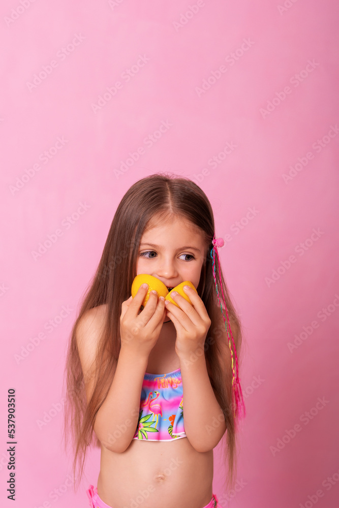 Caucasian beautiful little girl with fresh yellow lemons on a pink background. Little girl with lemon. Funny child isolated on pink. Caucasian beautiful little girl with fresh yellow lemons on a pink background. Little girl with lemon. Funny child isolated on pink.