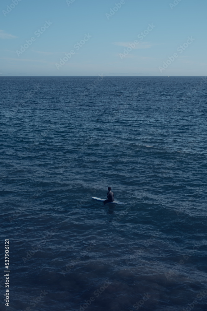 Alone surfer in the middle of the ocean while waiting for the perfect wave