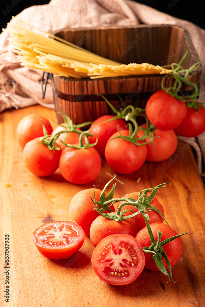 Pasta, beautiful details of red tomatoes and strands of raw spaghetti over rustic wood, selective focus. Pasta, beautiful details of red tomatoes and strands of raw spaghetti over rustic wood, selective focus.