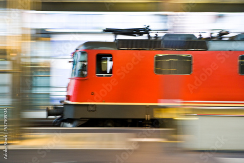 European train locomotive pulling into a passenger train station.