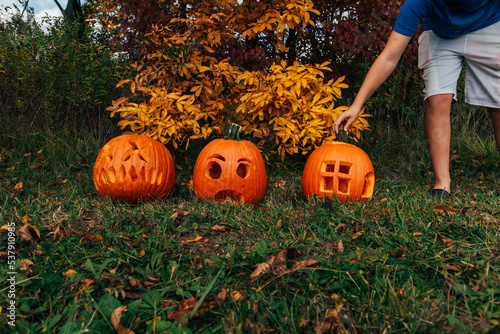 Boy reaching to adjust carved pumpkin stem. 