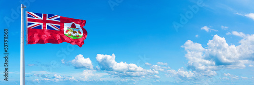 Bermuda flag waving on a blue sky in beautiful clouds - Horizontal banner