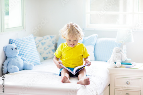 Child playing in bed. Kids room. Baby boy at home.