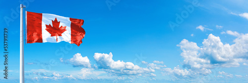 Canada flag waving on a blue sky in beautiful clouds - Horizontal banner