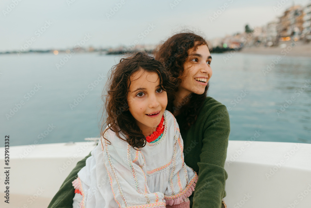 Woman and kid smiling aboard a small boat sailing on coastline Woman and kid smiling aboard a small boat sailing on coastline