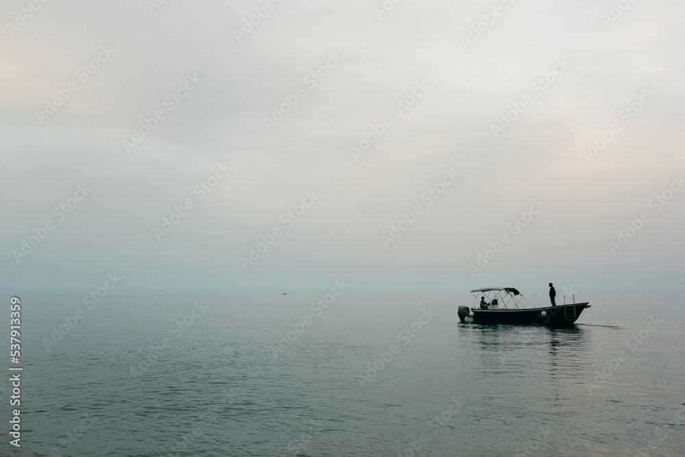 Seascape with silhouette of small motorboat at dusk Seascape with silhouette of small motorboat at dusk