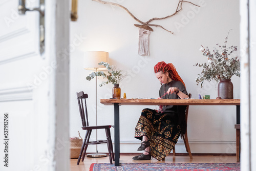 Female hippie sitting at table in home studio photo