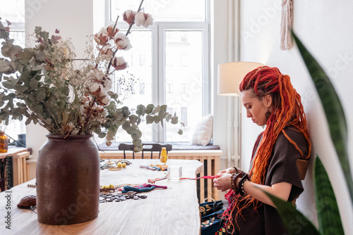 Craftswoman doing macrame against window