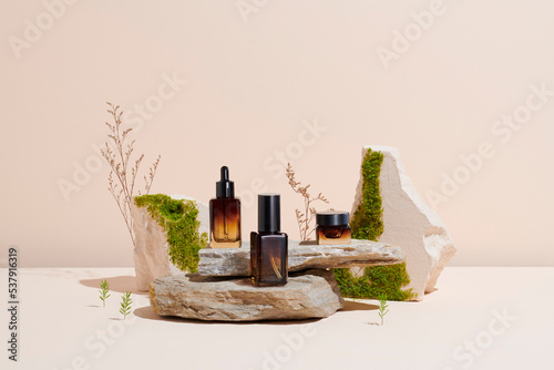 glass containers for natural cosmetics on a podium made of stones photo