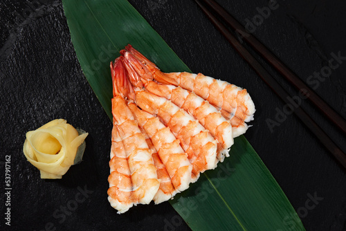 Sashimi with shrimps on bamboo leaf on black background
