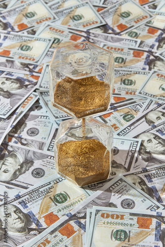 Close up of hourglass against bunch of dollars. photo