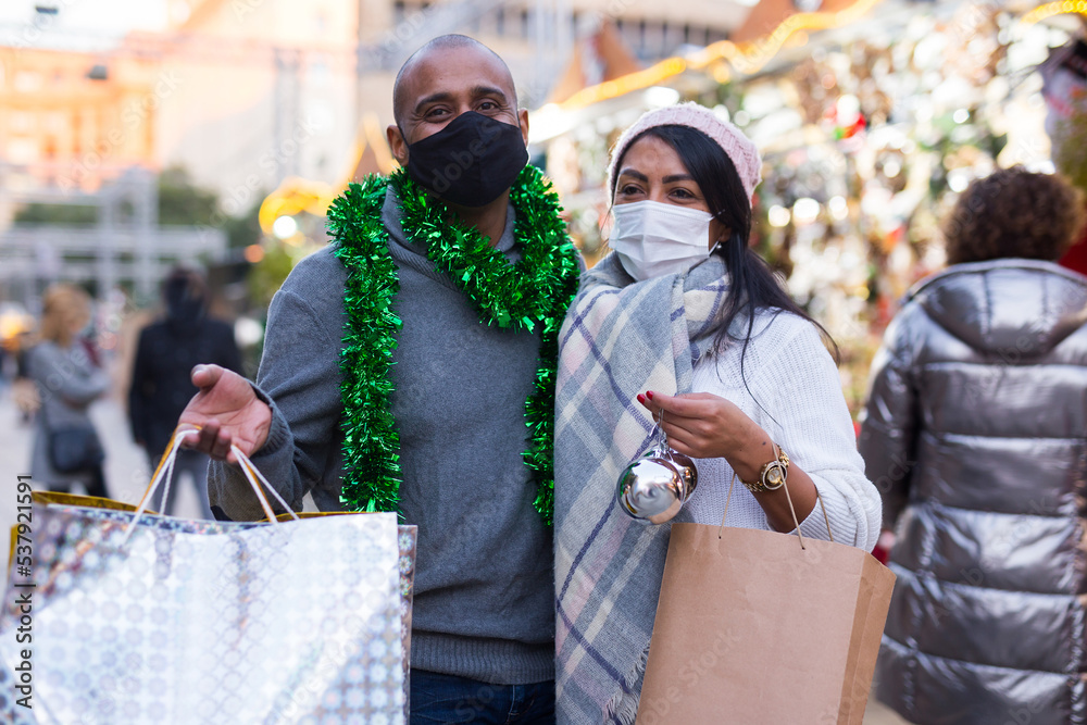 Married couple in protective masks with gifts at new year street fair