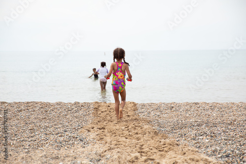 Children walking towards the lake on a pebbled white beach. photo