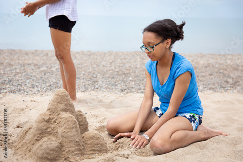 Teenage girl kneeling in the sand and making a sandcastle  photo