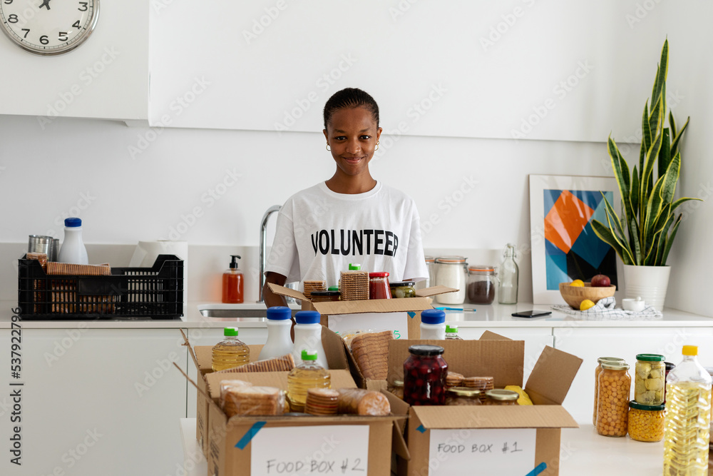 Volunteer preparing boxes with food at kitchen Volunteer preparing boxes with food at kitchen