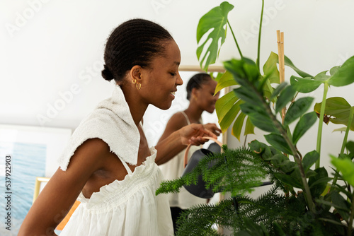 African woman watering plant indoor